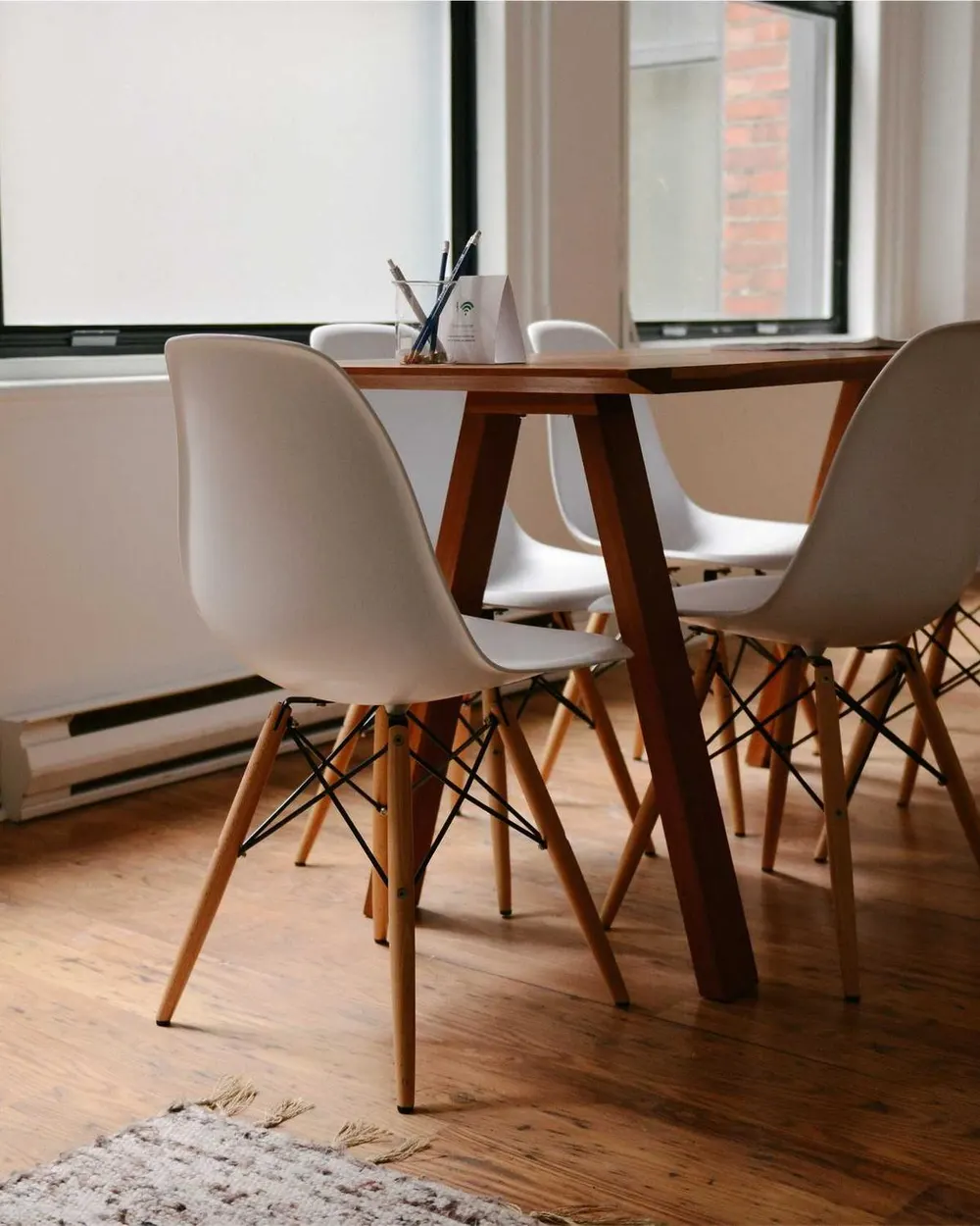 A bright room with a wooden table, white chairs and a wooden floor